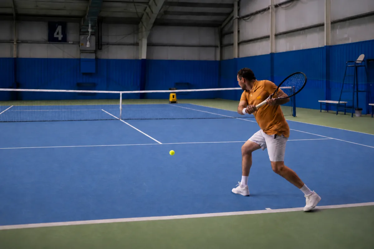 Player and yellow Sportbot training on a blue tennis court