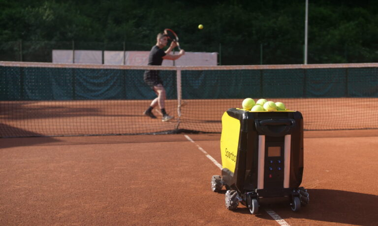 Tennis player playing backhand slice with a tennis ball machine