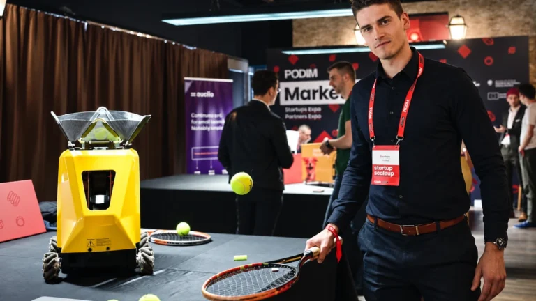 Sportbot founder standing beside the Sportbot machine at a conference stand